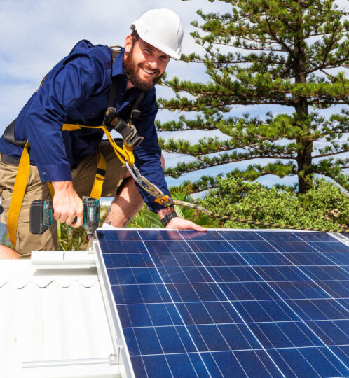 Man on rooftop installing solar panels