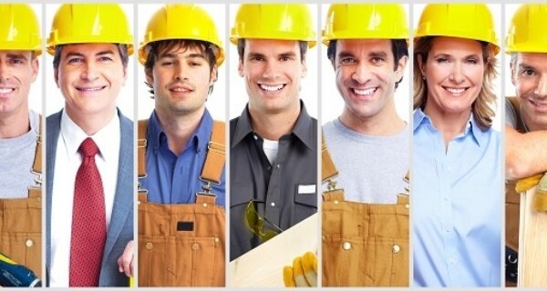 Row of construction workers wearing yellow hard hats and work uniforms, smiling at the camera.