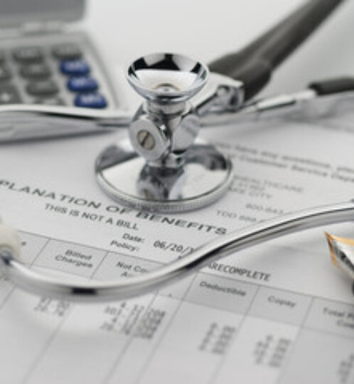 Stethoscope resting on a medical form with a pen and a calculator visible in the background, suggesting healthcare paperwork.