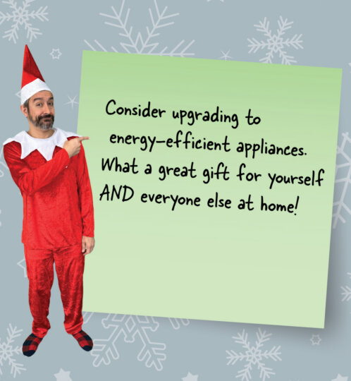 Man in a red elf costume points to a pale green sticky note with handwritten text about upgrading to energy-efficient appliances; snowy blue background.