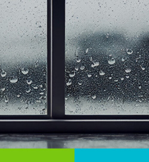 Three-panel window with raindrops on the glass and a blurry outdoor scene beyond; a lime green and cyan bar runs along the bottom edge.