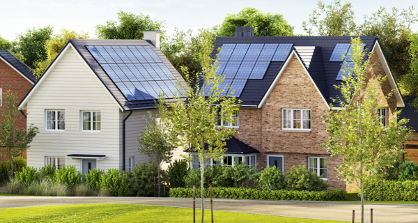 Two modern houses in a suburban setting with solar panels on their roofs, surrounded by trees, shrubs, and a neatly kept lawn.