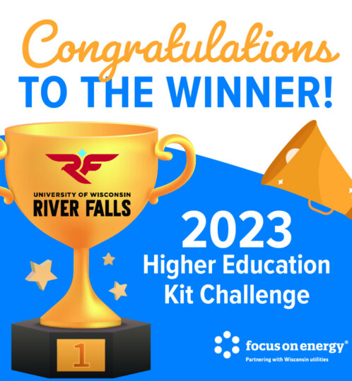 Gold trophy with River Falls logo, bold blue TO THE WINNER text, 2023 Higher Education Kit Challenge, plus a megaphone and an energy partner logo.
