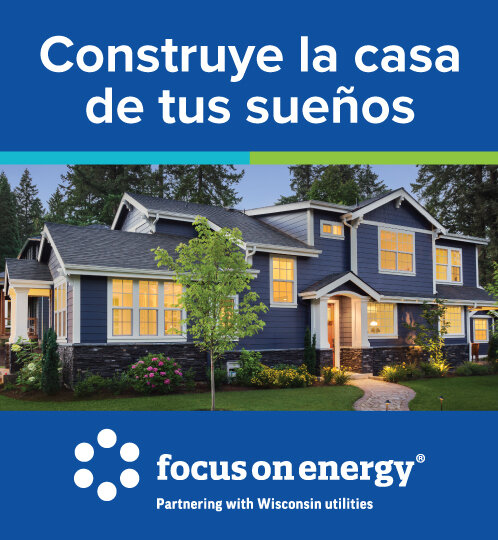 Two-story blue house with warm-lit windows on a landscaped lawn, beneath a blue banner with Spanish text; bottom displays the Focus on Energy logo.