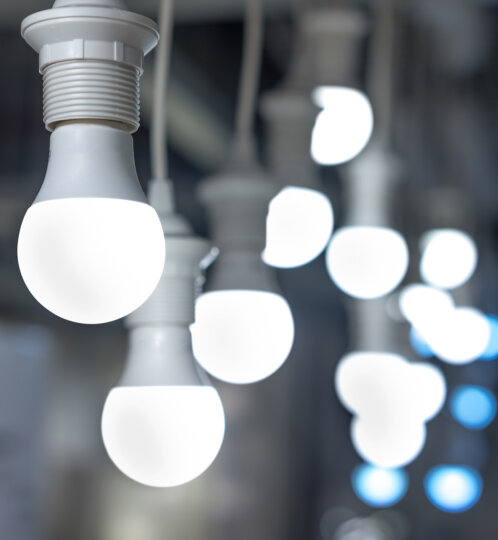 Close-up of white light bulbs hanging in a row; the front bulb is in sharp focus while others blur into glowing orbs in the background.