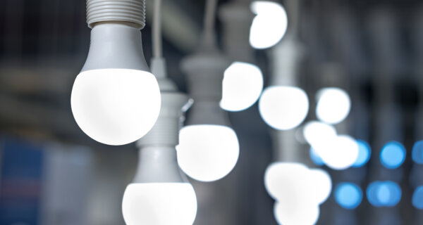 Close-up of white light bulbs hanging in a row; the front bulb is in sharp focus while others blur into glowing orbs in the background.