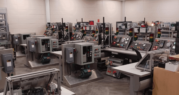 Industrial control room filled with rows of consoles, panels, gauges, and motors in a lab-like workshop.