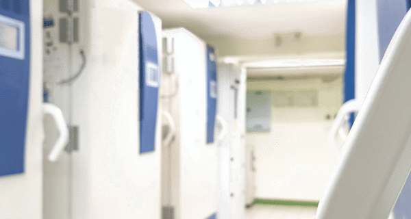 Bright corridor with tall blue-and-white machines aligned along the left wall; a large curved white element frames the right foreground.