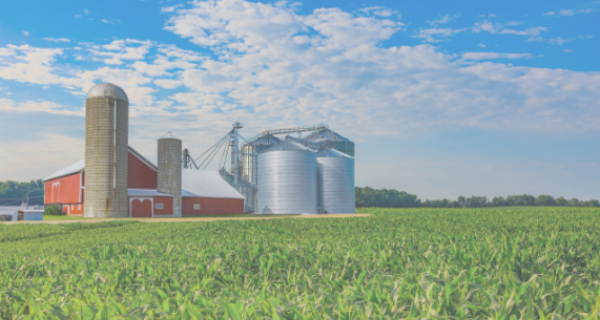 Farm scene with a red barn and silos beside a lush green crop field under a blue sky with clouds; Focus on Energy logo at bottom right.